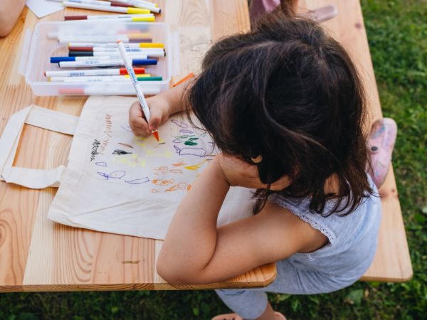 Ein Kind, von oben, malt auf eine Papiertüte